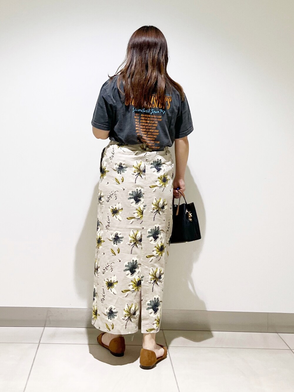 オレンジ系のTシャツ/カットソー、ブラック系のハンドバッグ、イエロー系のスカートを着用したレディースの夏コーディネートの5枚目の写真