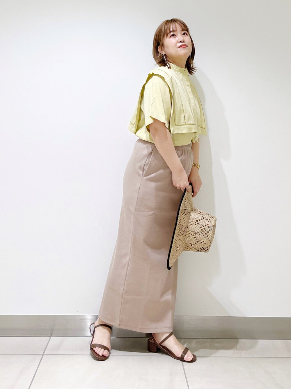 イエロー系のシャツ/ブラウス、ブラウン系のサンダル、ベージュ系のスカートを着用したレディースの夏コーディネートの5枚目の写真