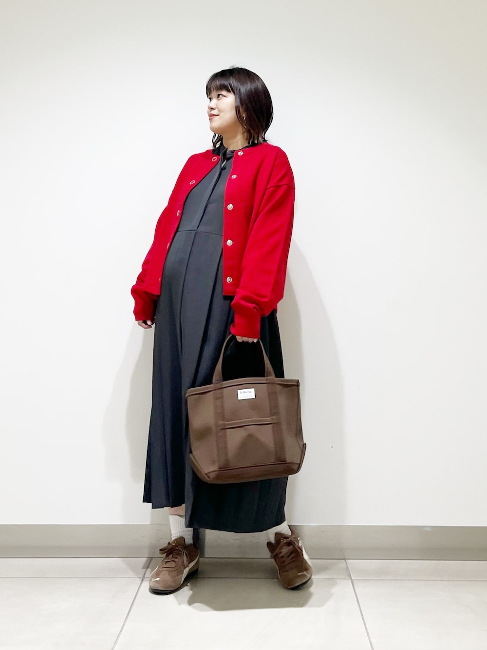 グレー系のワンピース、ブラウン系のトートバッグ、レッド系のカーディガン/ボレロを着用したレディースの秋コーディネートの6枚目の写真