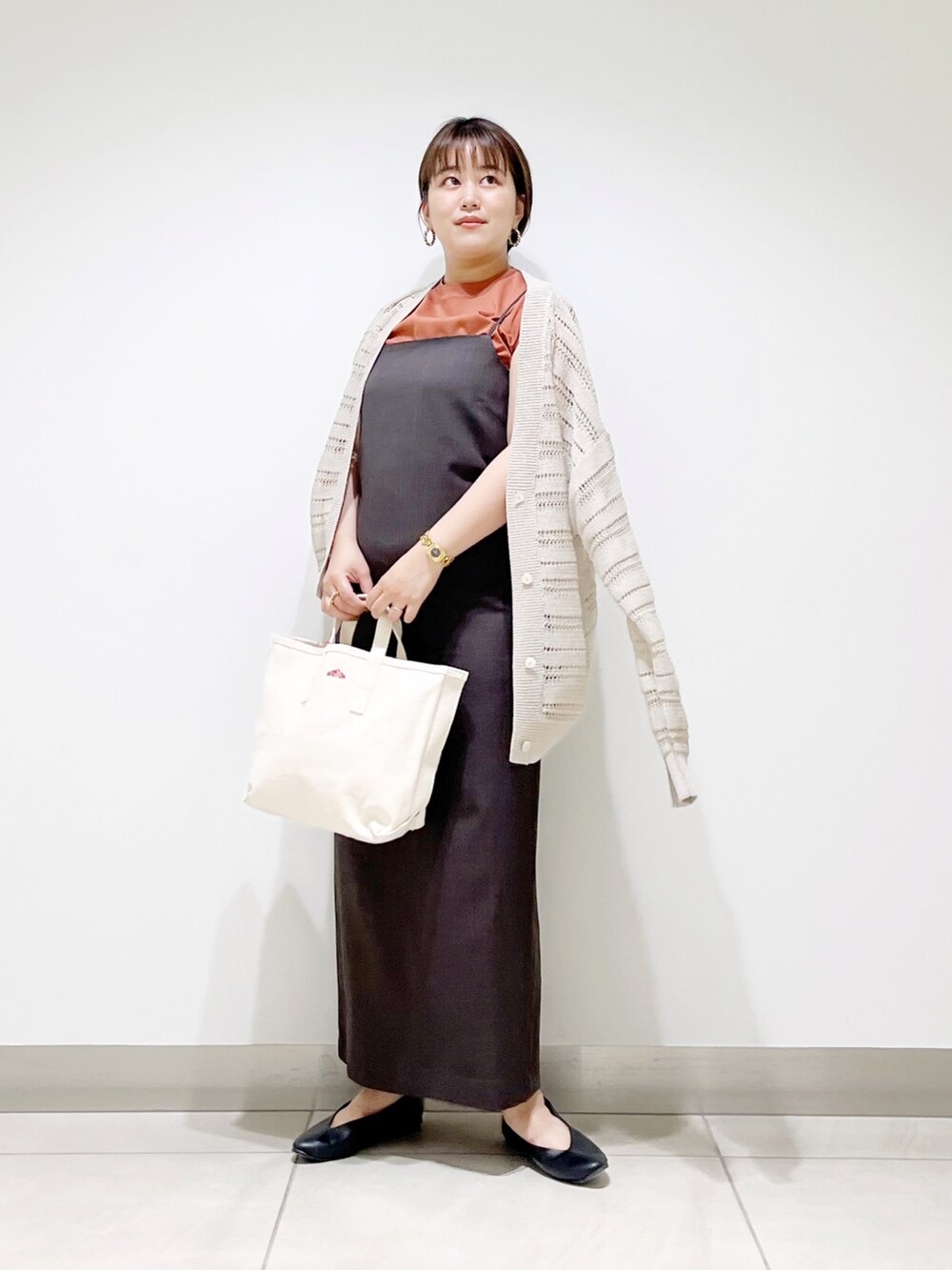 グレー系のワンピース、ホワイト系のトートバッグ、ブラック系のパンプスを着用したレディースの夏コーディネートの2枚目の写真