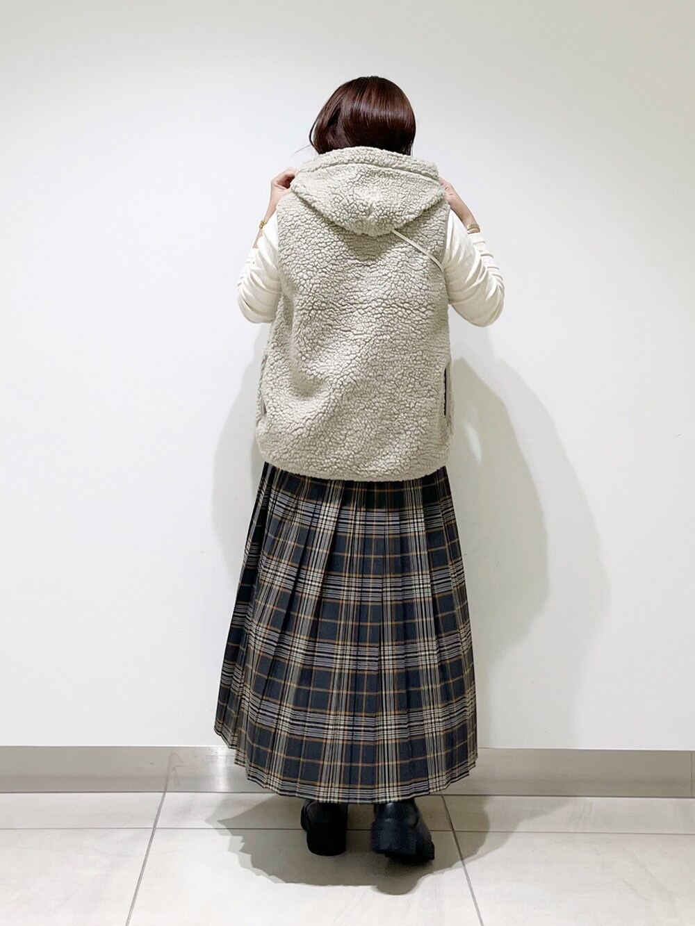 ホワイト系のトップス、グレー系のスカート、ブラック系のブーツを着用したレディースの秋コーディネートの8枚目の写真