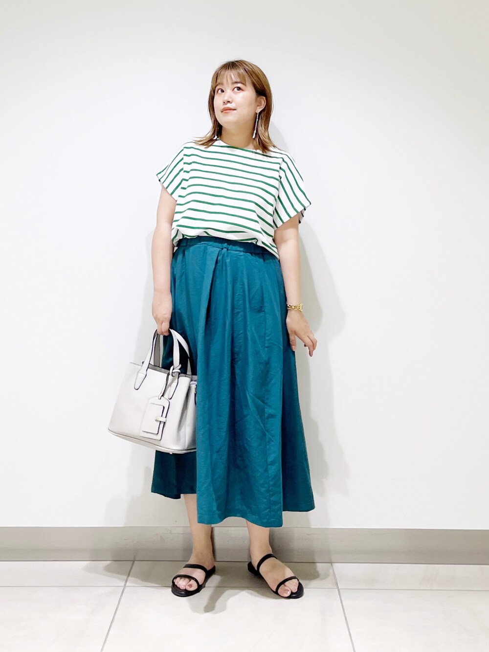 グリーン系のTシャツ/カットソー、グリーン系のスカート、グレー系のトートバッグを着用したレディースの夏コーディネートの2枚目の写真