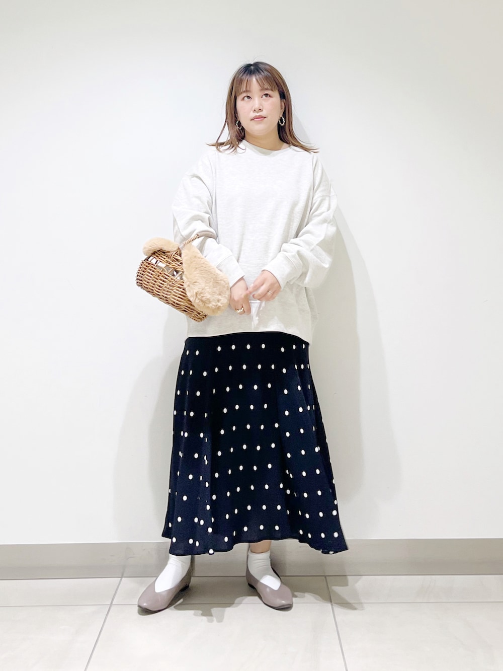 グレー系のスウェット、ベージュ系のかごバッグ、ブラック系のスカートを着用したレディースの秋コーディネートの2枚目の写真