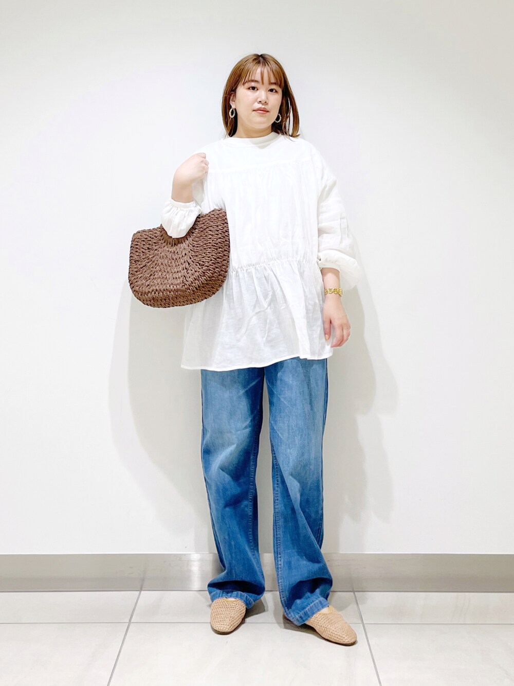 ホワイト系のシャツ/ブラウス、ブラウン系のハンドバッグ、ブルー系のデニムパンツを着用したレディースの春コーディネートの5枚目の写真