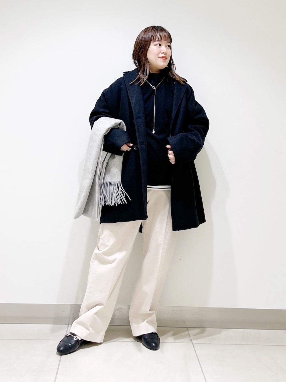 ブルー系のピーコート、ブラック系のニット/セーター、ホワイト系のTシャツ/カットソーを着用したレディースの冬コーディネートの2枚目の写真