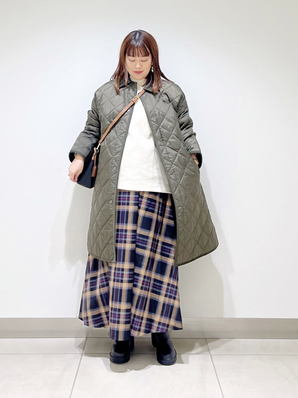 グリーン系のダウンジャケット/コート、ホワイト系のトップス、ブラウン系のスカートを着用したレディースの秋コーディネートの10枚目の写真
