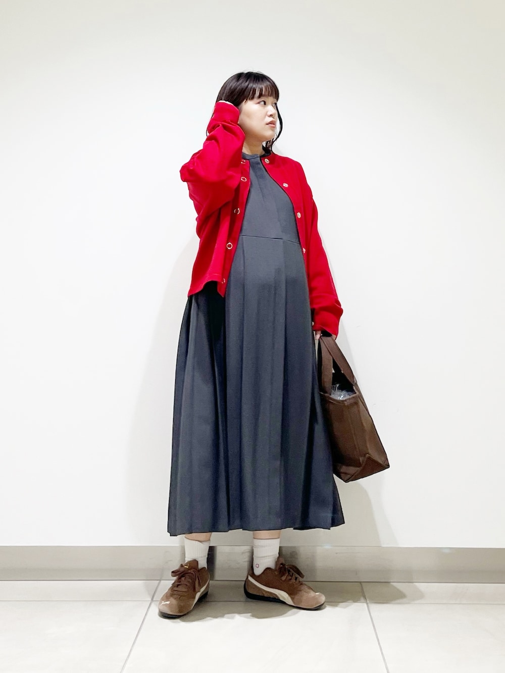 グレー系のワンピース、ブラウン系のトートバッグ、レッド系のカーディガン/ボレロを着用したレディースの秋コーディネートの3枚目の写真