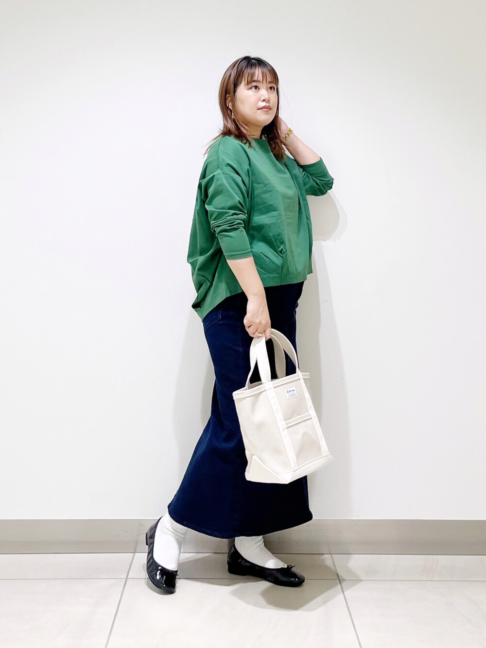 グリーン系のTシャツ/カットソー、ブルー系のスカート、ホワイト系のトートバッグを着用したレディースの秋コーディネートの4枚目の写真