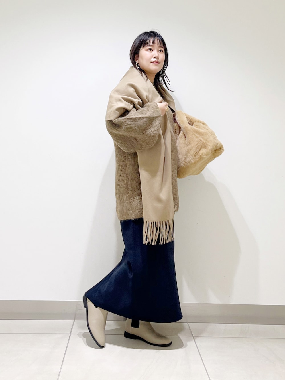 ブラウン系のニット/セーター、イエロー系のハンドバッグ、ブラック系のスカートを着用したレディースの冬コーディネートの3枚目の写真