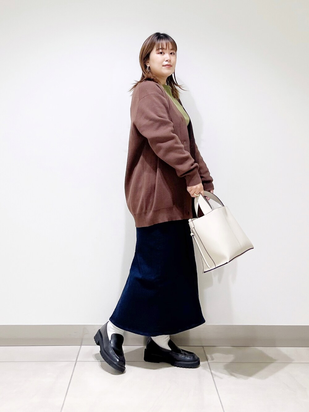 ブラウン系のカーディガン/ボレロ、グリーン系のTシャツ/カットソー、ホワイト系のトートバッグを着用したレディースの秋コーディネートの5枚目の写真