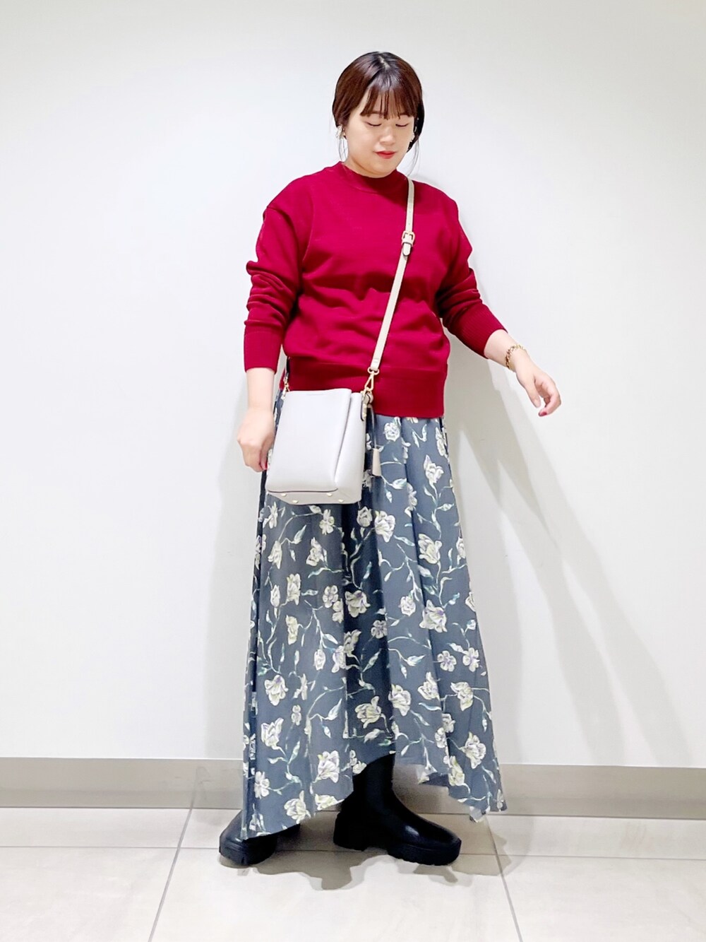 レッド系のトップス、グレー系のスカート、グレー系のショルダーバッグを着用したレディースの秋コーディネートの9枚目の写真