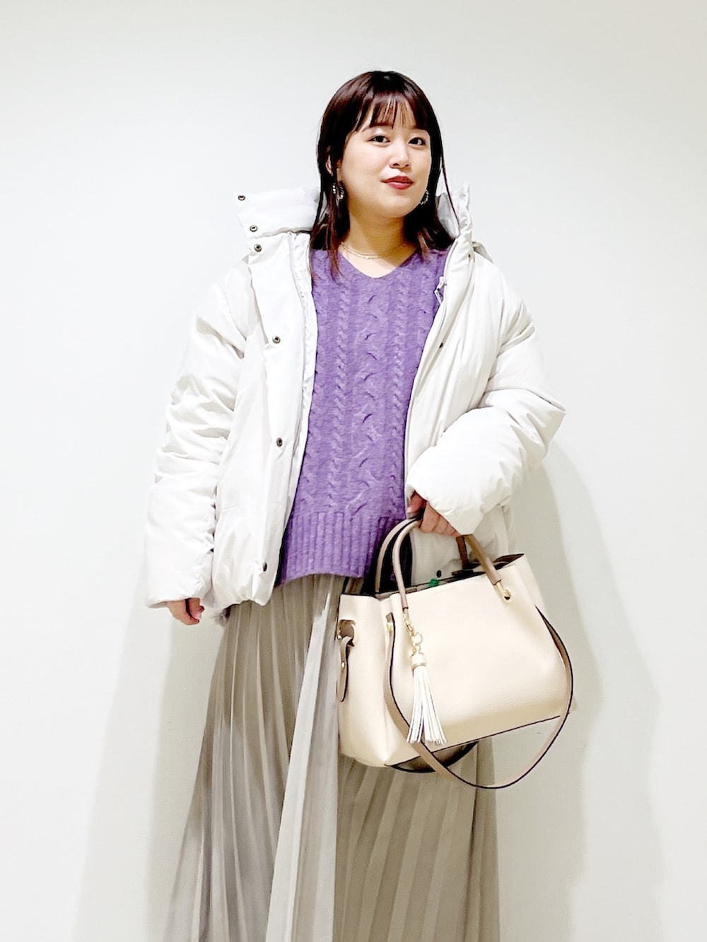 ホワイト系のダウンジャケット/コート、パープル系のニット/セーター、ベージュ系のスカートを着用したレディースの冬コーディネートの4枚目の写真