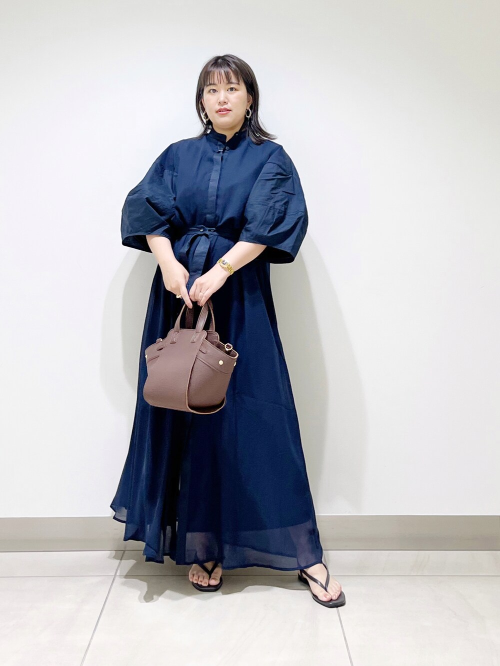 ブルー系のワンピース、ブラウン系のハンドバッグ、ブラック系のサンダルを着用したレディースの夏コーディネートの4枚目の写真