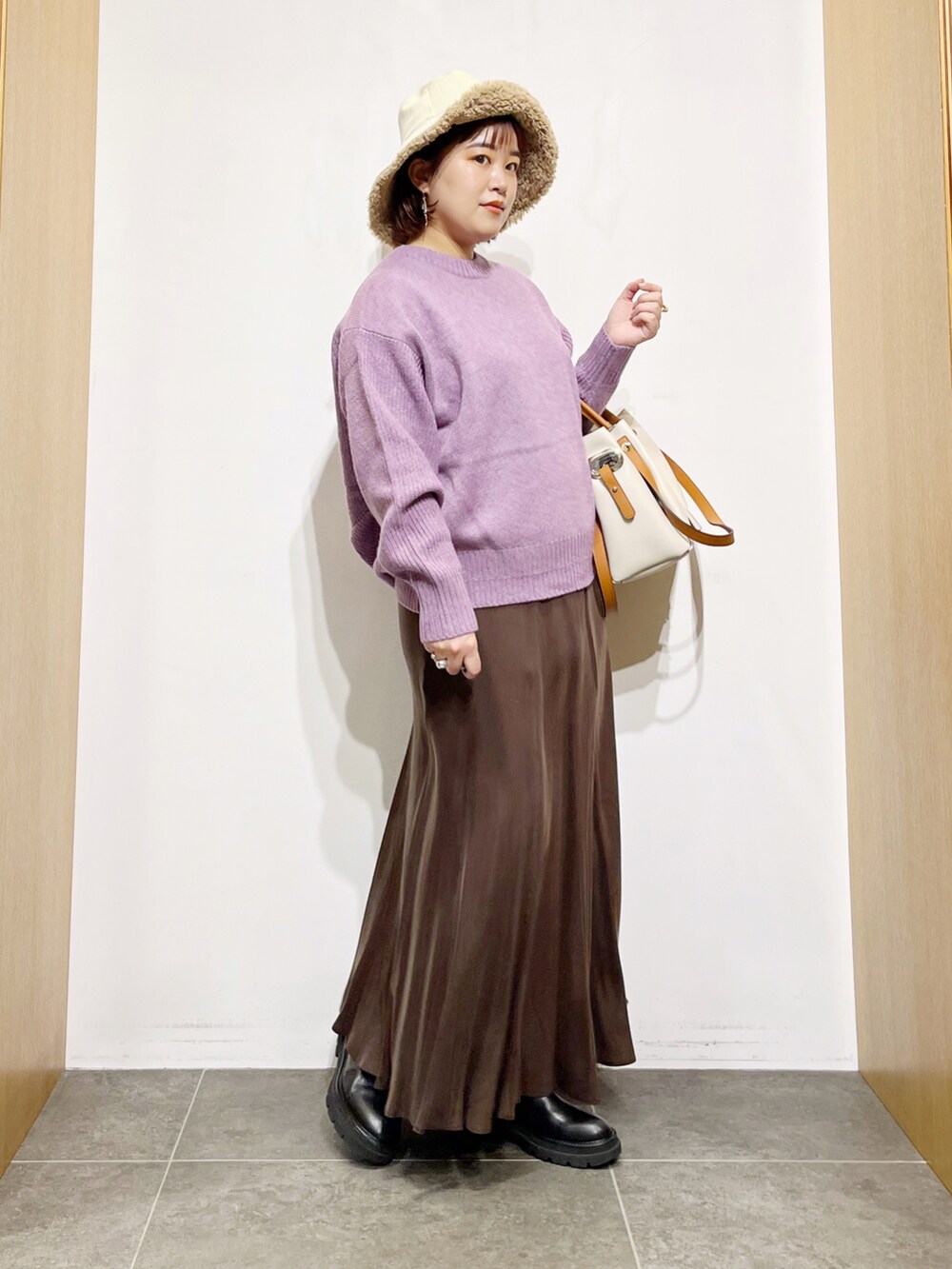 パープル系のニット/セーター、ブラウン系のスカート、ホワイト系のトートバッグを着用したレディースの冬コーディネートの4枚目の写真