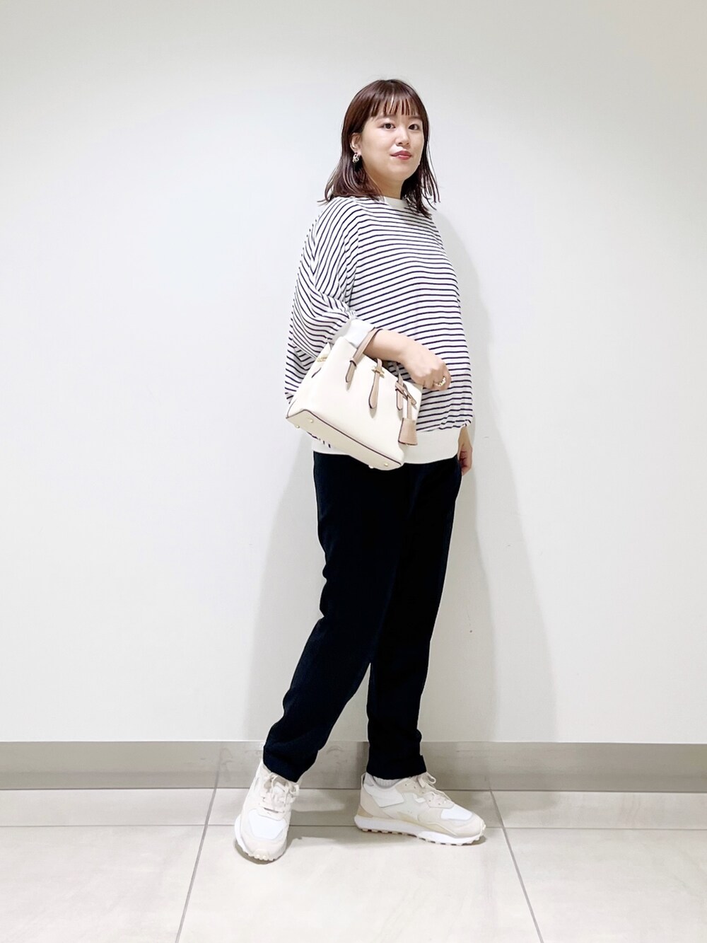 ホワイト系のTシャツ/カットソー、ブルー系のパンツ、ホワイト系のハンドバッグを着用したレディースの秋コーディネートの7枚目の写真