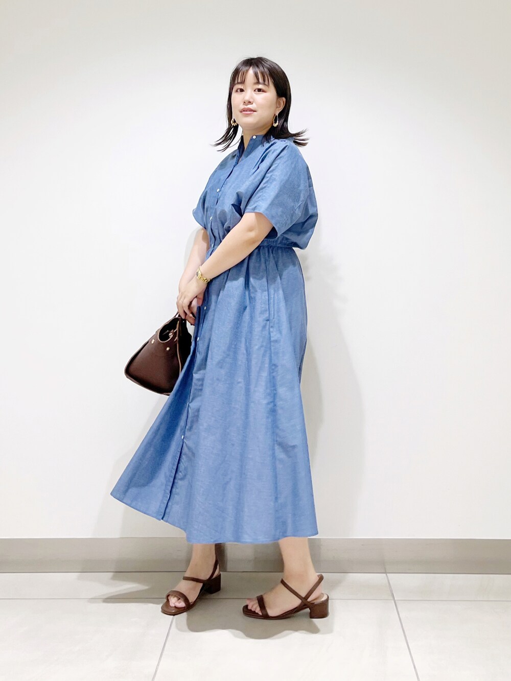 ブルー系のワンピース、ブラウン系のハンドバッグ、ブラウン系のサンダルを着用したレディースの夏コーディネートの2枚目の写真