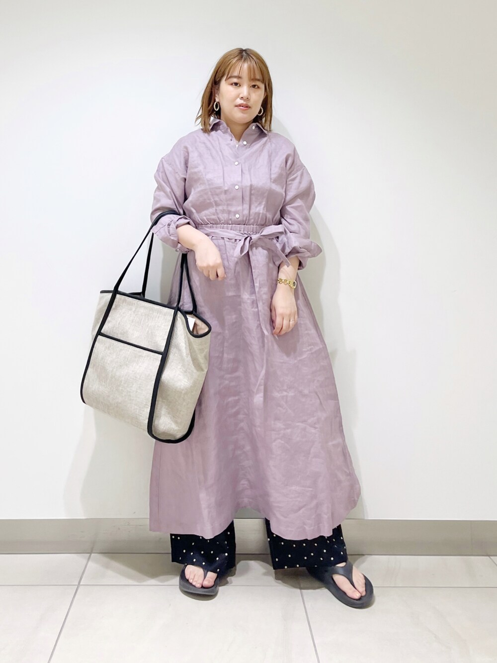 パープル系のワンピース、ブラック系のトートバッグ、ブラック系のサンダルを着用したレディースの春コーディネートの2枚目の写真