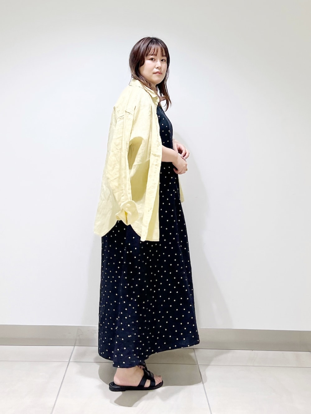 ブラック系のワンピース、イエロー系のシャツ/ブラウス、ブラック系のサンダルを着用したレディースの春コーディネートの3枚目の写真