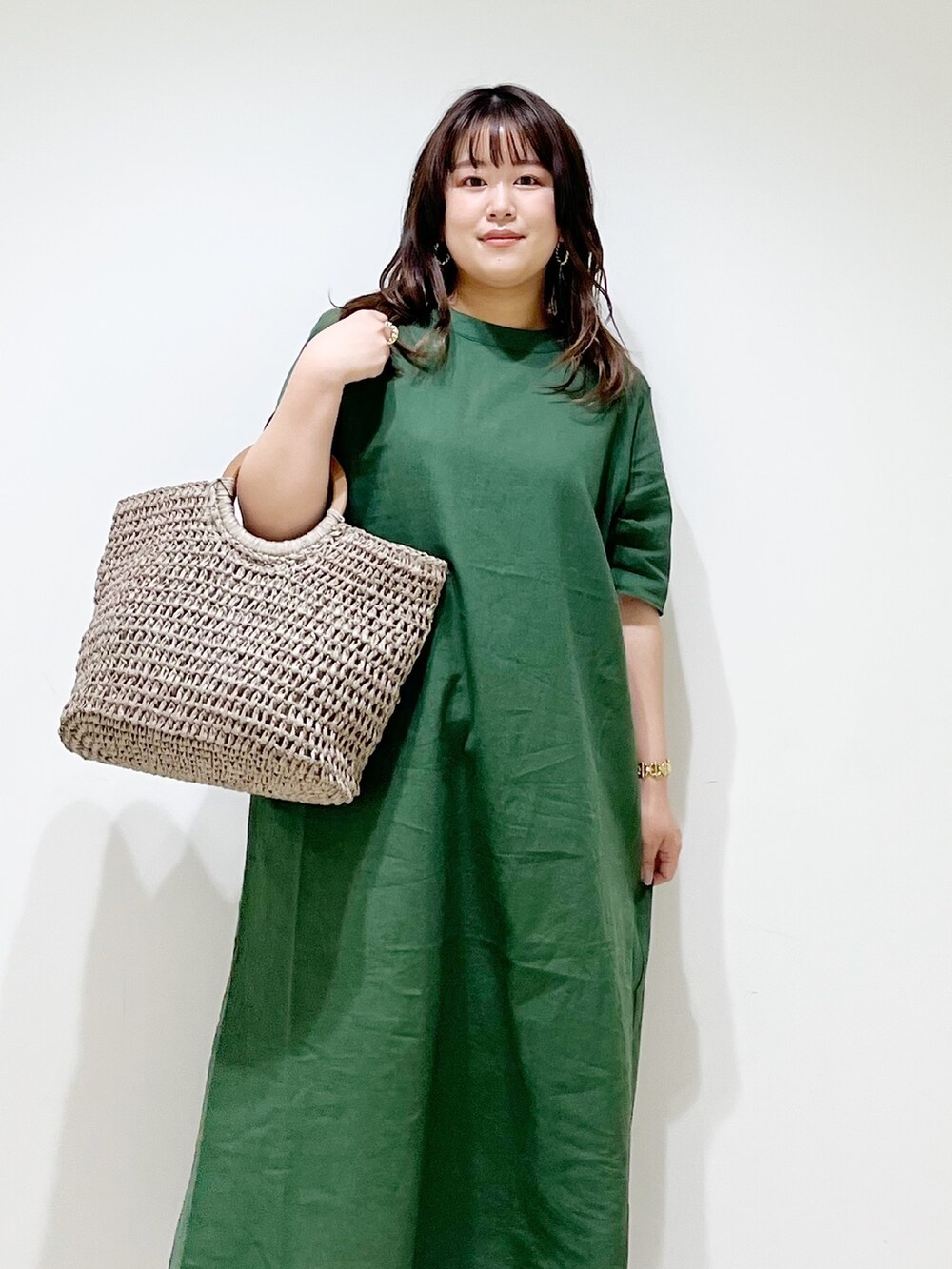 グリーン系のワンピース、グレー系のかごバッグ、ホワイト系のスニーカーを着用したレディースの夏コーディネートの6枚目の写真