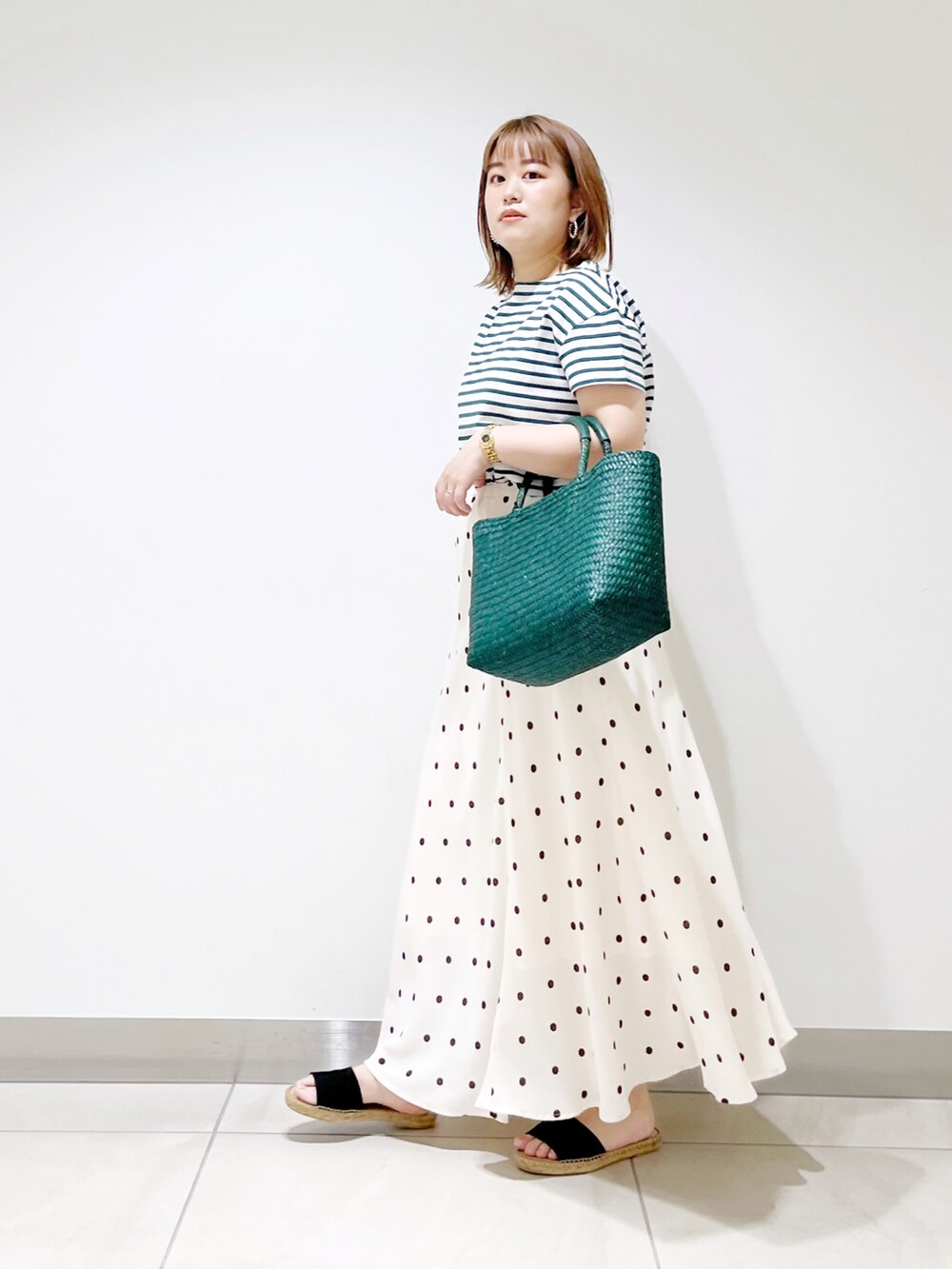 ホワイト系のスカート、グリーン系のかごバッグ、グリーン系のTシャツ/カットソーを着用したレディースの春コーディネートの4枚目の写真