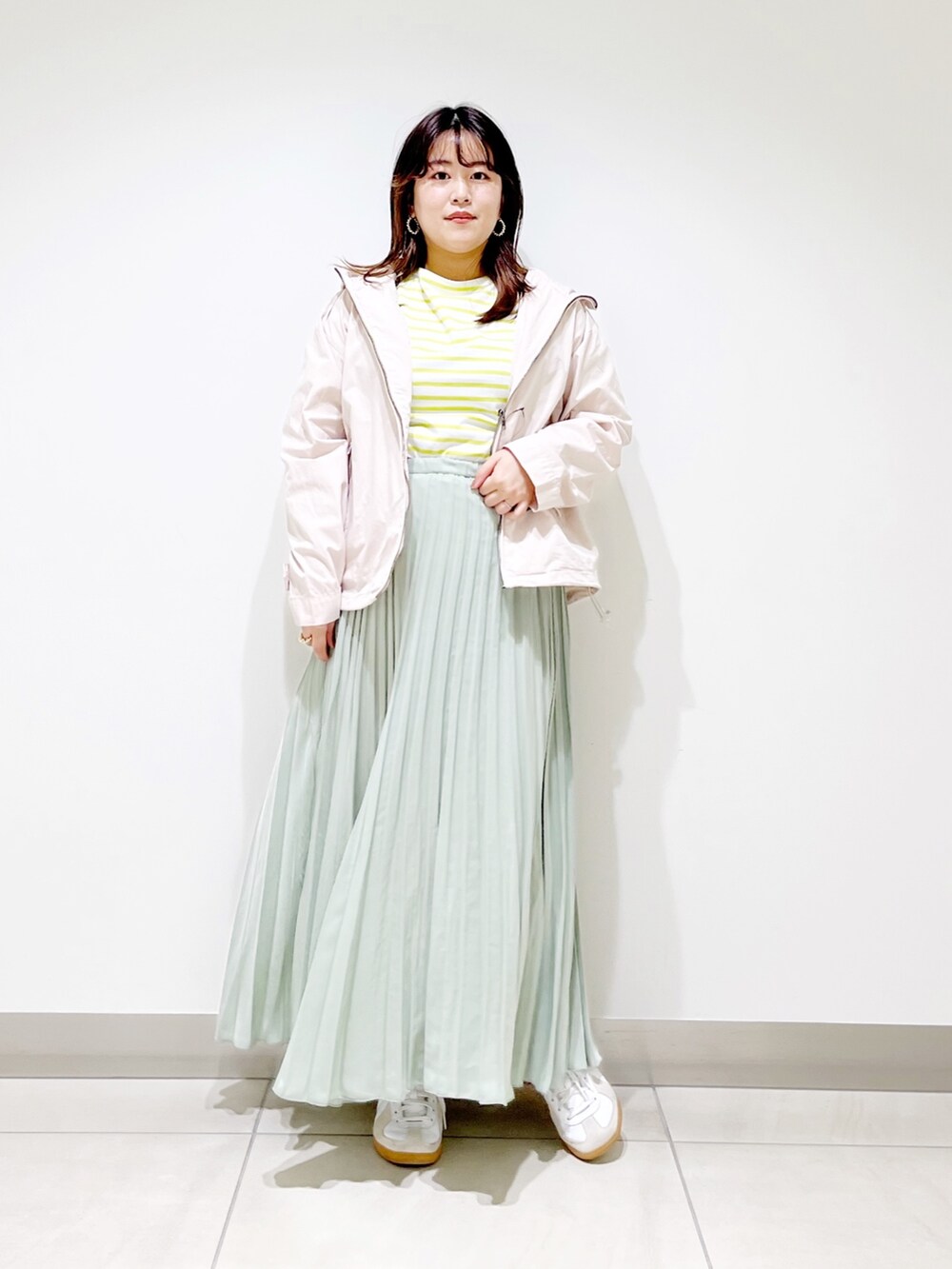 ベージュ系のブルゾン、イエロー系のTシャツ/カットソー、グリーン系のスカートを着用したレディースの春コーディネートの4枚目の写真