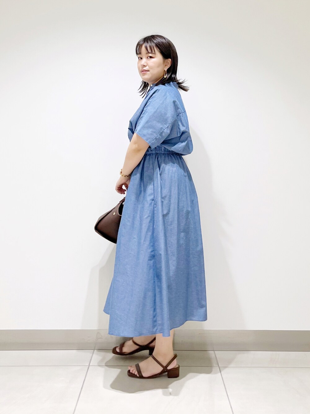 ブルー系のワンピース、ブラウン系のハンドバッグ、ブラウン系のサンダルを着用したレディースの夏コーディネートの4枚目の写真