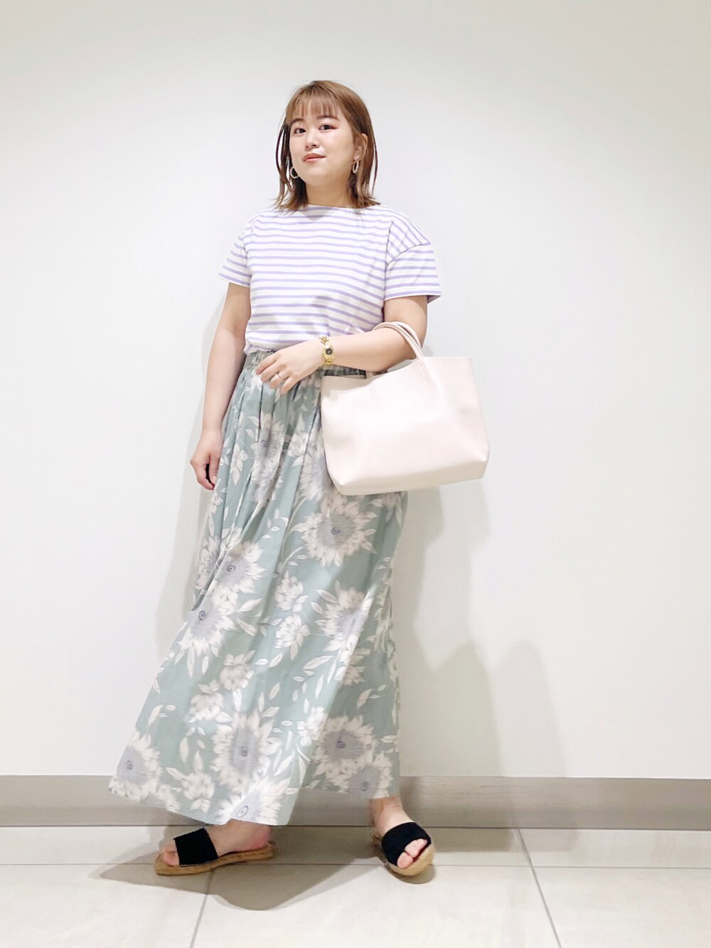 グリーン系のスカート、パープル系のTシャツ/カットソー、ホワイト系のトートバッグを着用したレディースの春コーディネートの5枚目の写真