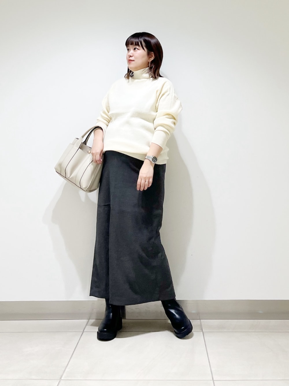 ホワイト系のニット/セーター、ホワイト系のトートバッグ、グレー系のスカートを着用したレディースの秋コーディネートの2枚目の写真