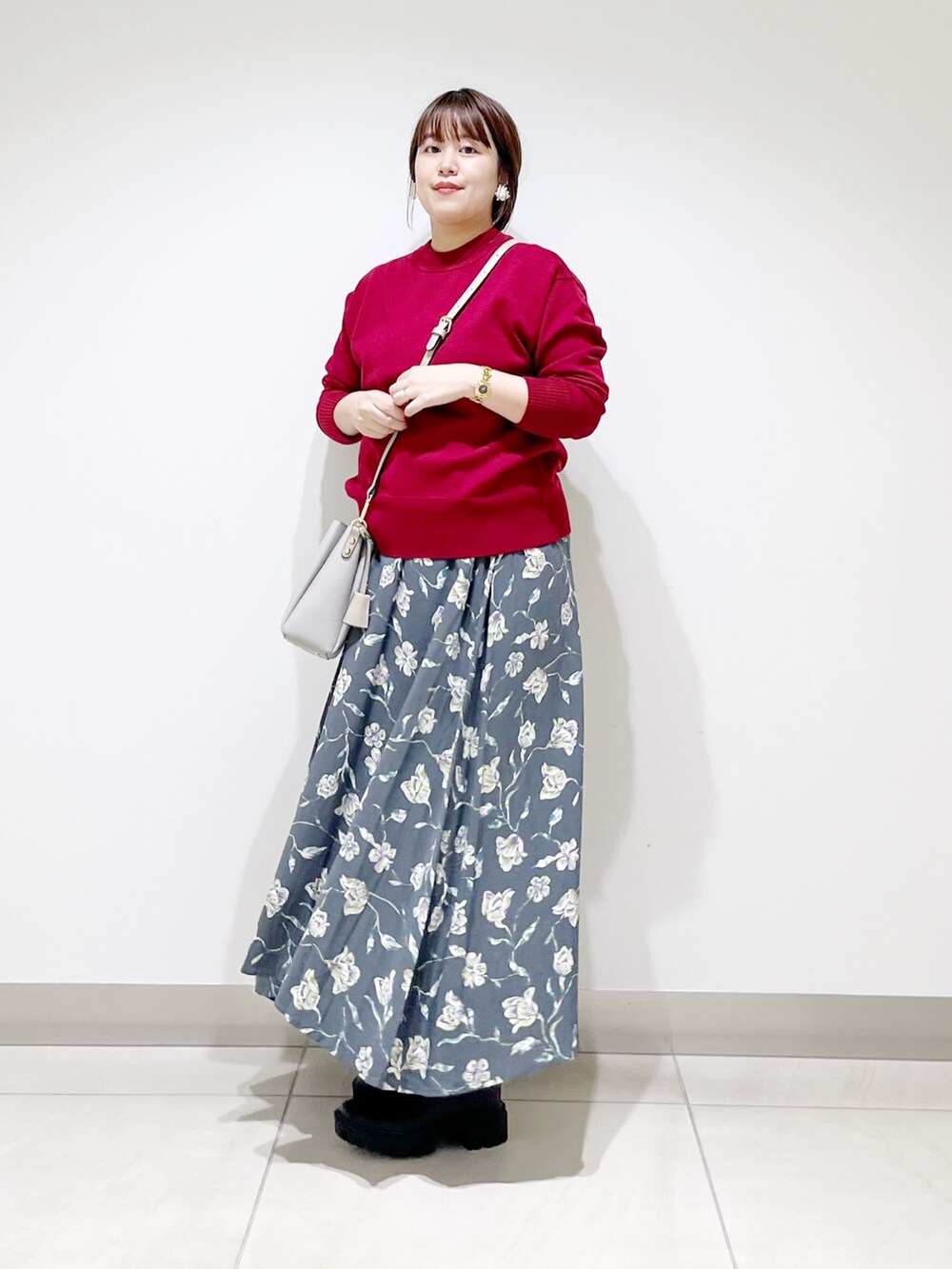 レッド系のトップス、グレー系のスカート、グレー系のショルダーバッグを着用したレディースの秋コーディネートの7枚目の写真