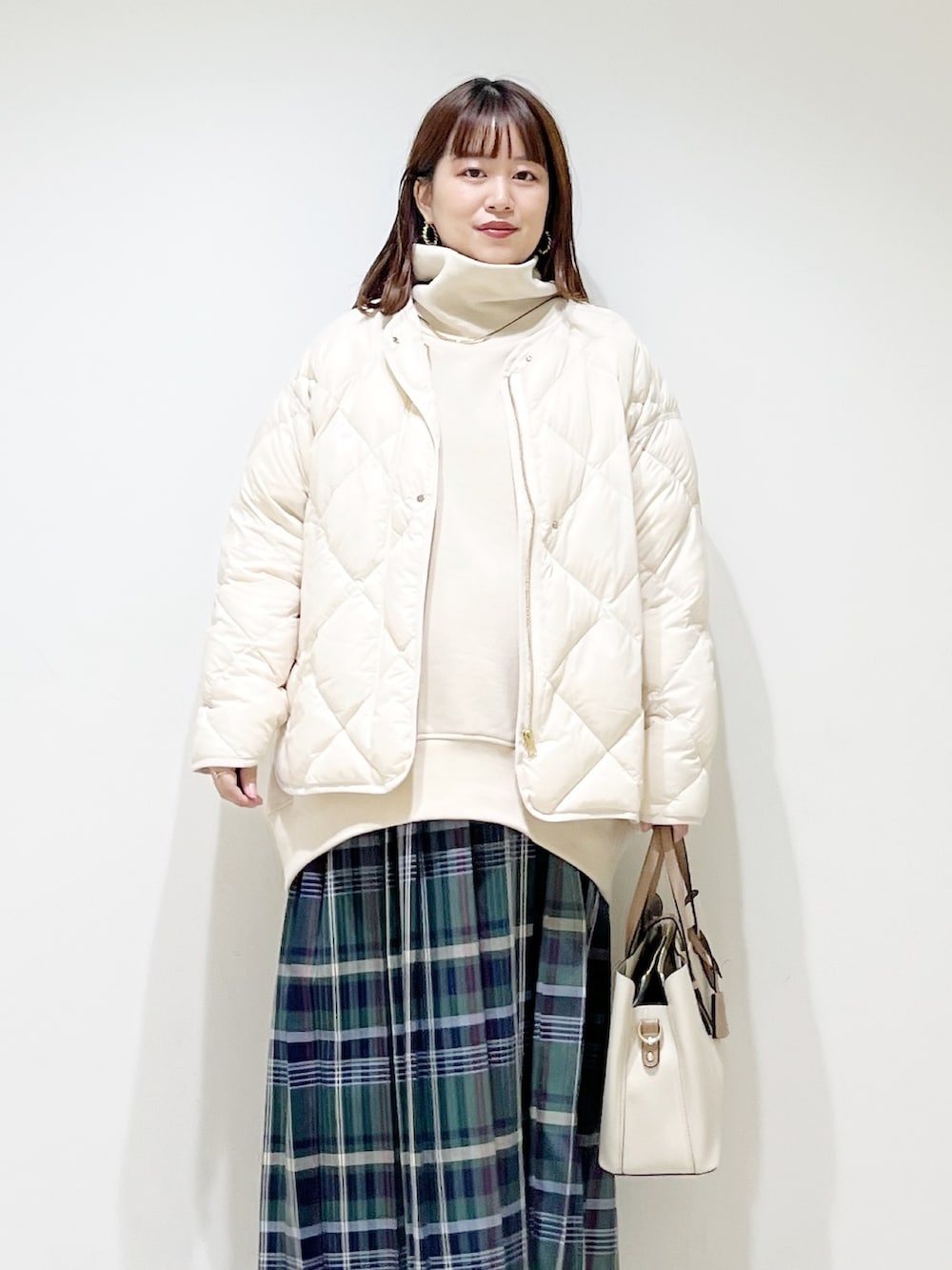 ベージュ系のスウェット、ホワイト系のダウンジャケット/コート、グリーン系のスカートを着用したレディースの秋コーディネートの4枚目の写真