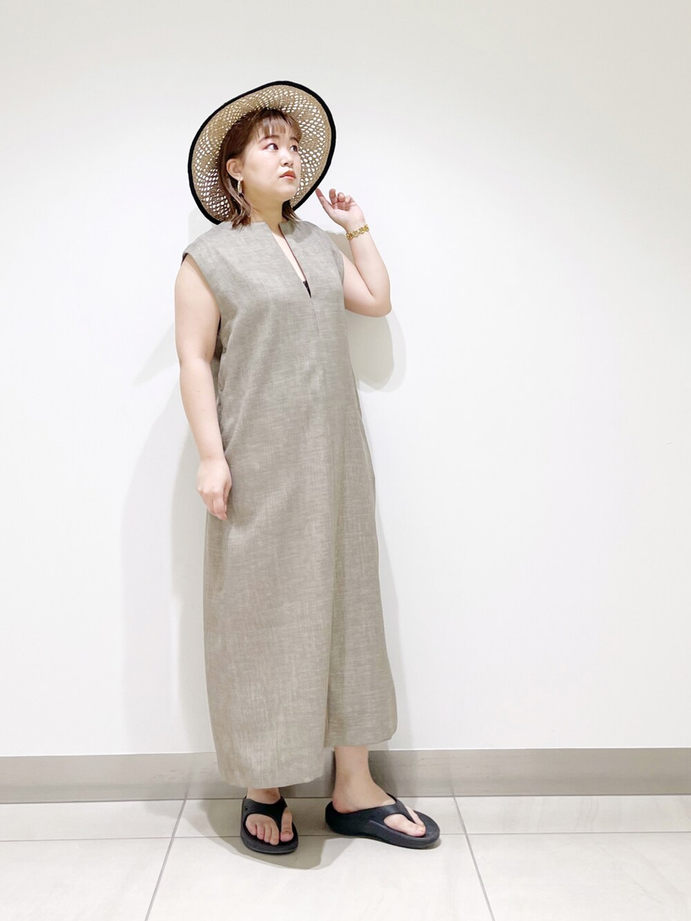 グレー系のワンピース、ブラック系のサンダル、ブラック系のハットを着用したレディースの春コーディネートの4枚目の写真