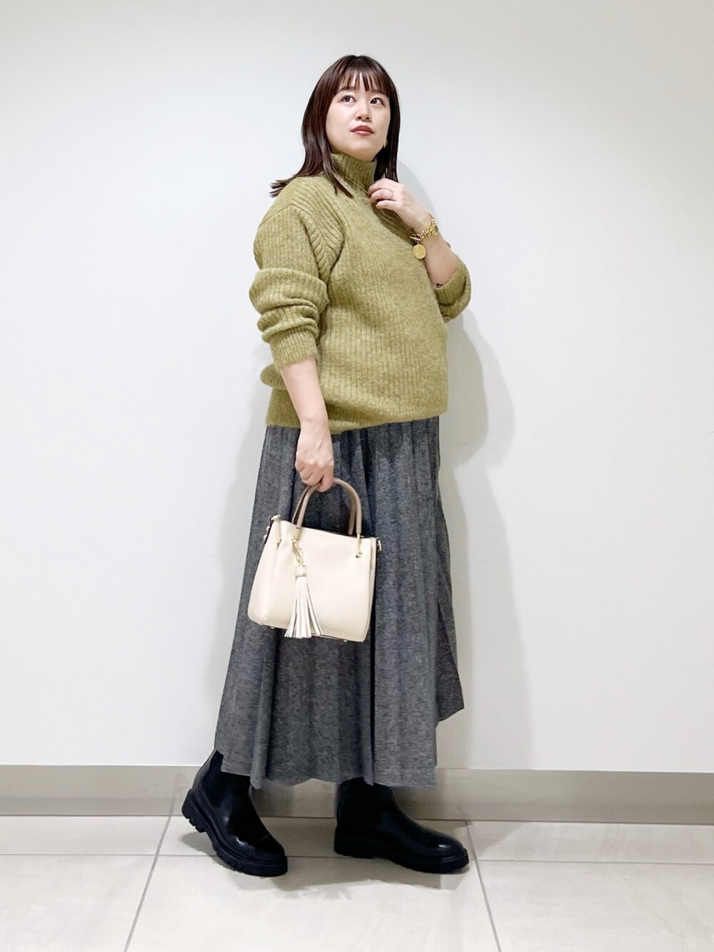 グリーン系のニット/セーター、ブルー系のスカート、ホワイト系のトートバッグを着用したレディースの冬コーディネートの7枚目の写真