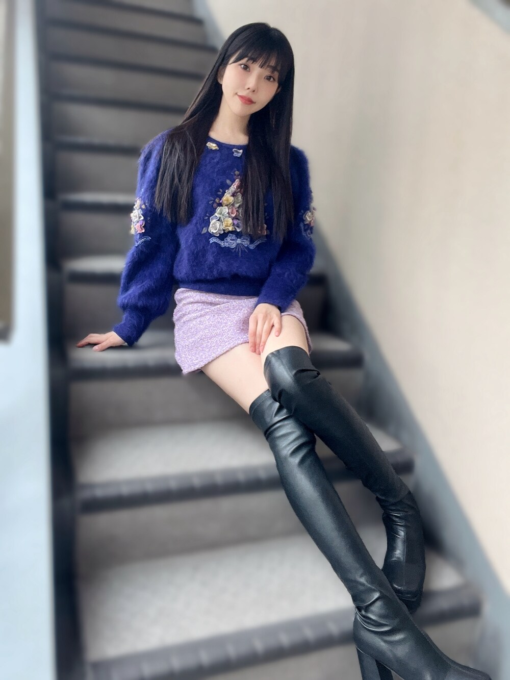 ブラック系のブーツ、ピンク系のスカート、パープル系のニット/セーターを着用したレディースの冬コーディネートの2枚目の写真