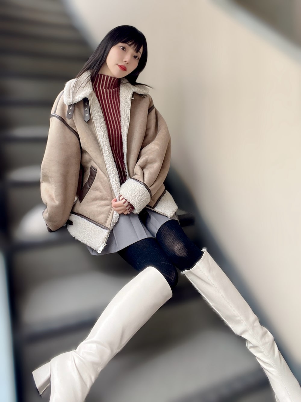 ホワイト系のブーツ、グレー系のスカート、レッド系のニット/セーターを着用したレディースの冬コーディネートの2枚目の写真