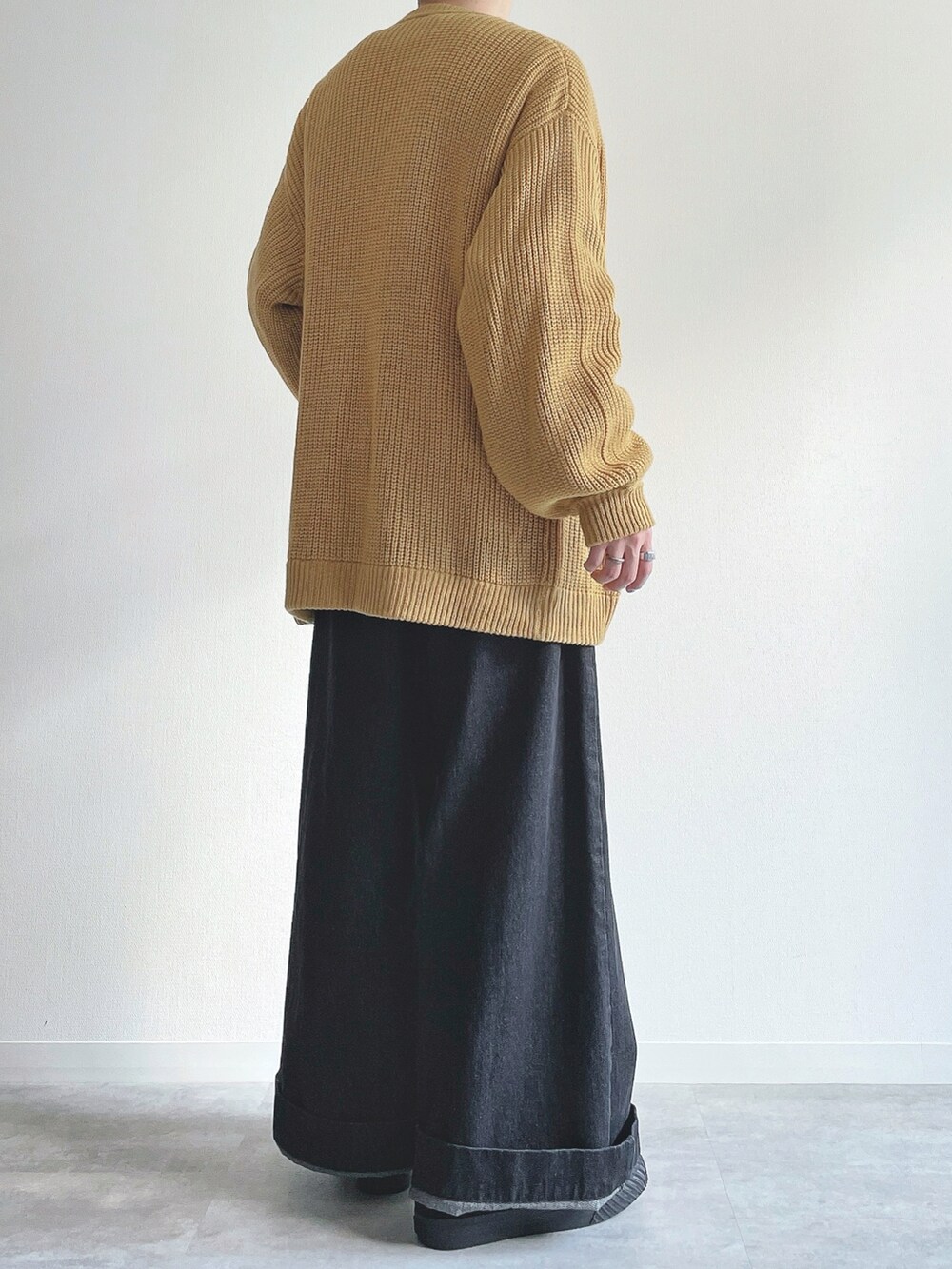 イエロー系のカーディガン/ボレロ、グレー系のトップス、ブラック系のデニムパンツを着用したメンズの秋コーディネートの4枚目の写真