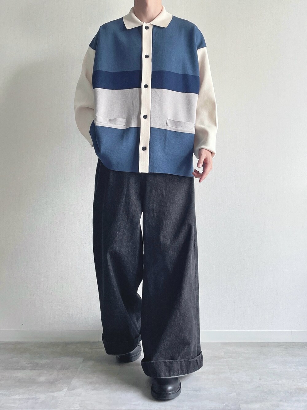 ブルー系のポロシャツ、ブラック系のデニムパンツ、ブラック系のシューズを着用したメンズの秋コーディネートの2枚目の写真