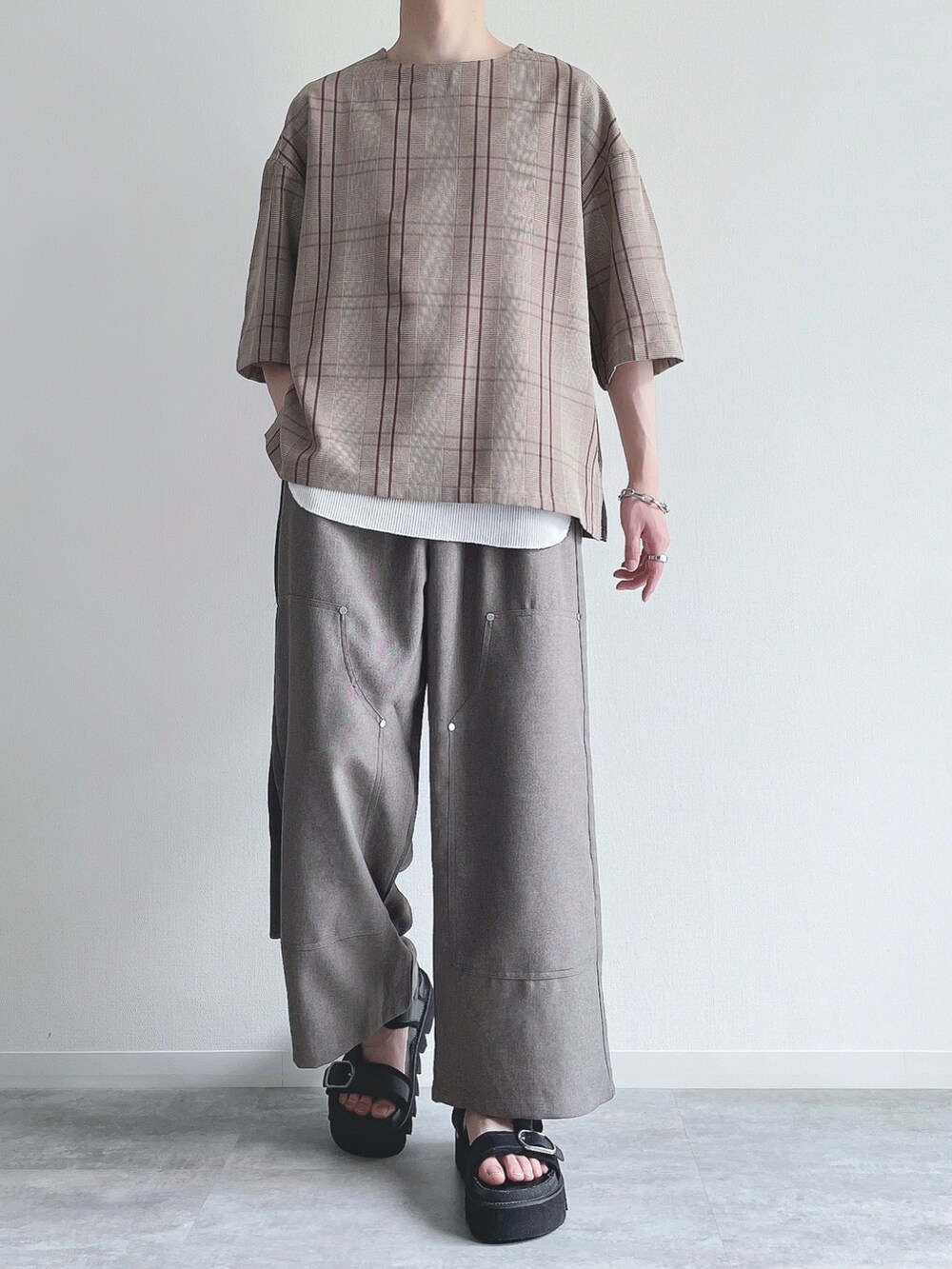 ブラウン系のTシャツ/カットソー、ホワイト系のタンクトップ、ベージュ系のスラックスを着用したメンズの夏コーディネートの2枚目の写真