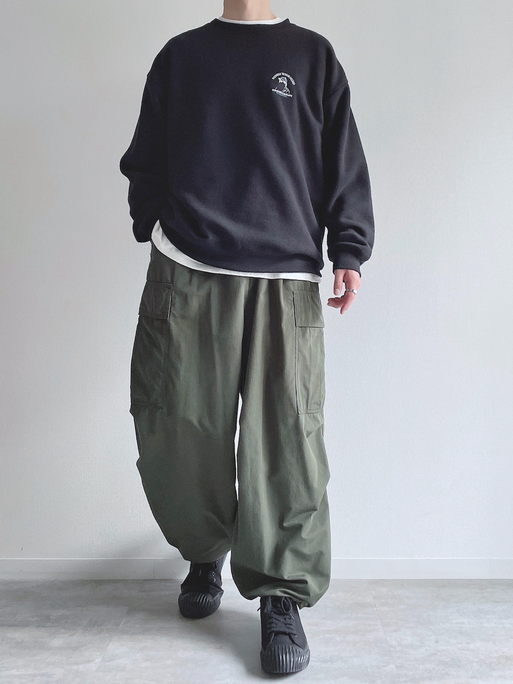 ブラック系のスウェット、ホワイト系のTシャツ/カットソー、グリーン系のカーゴパンツを着用したメンズの春コーディネートの4枚目の写真
