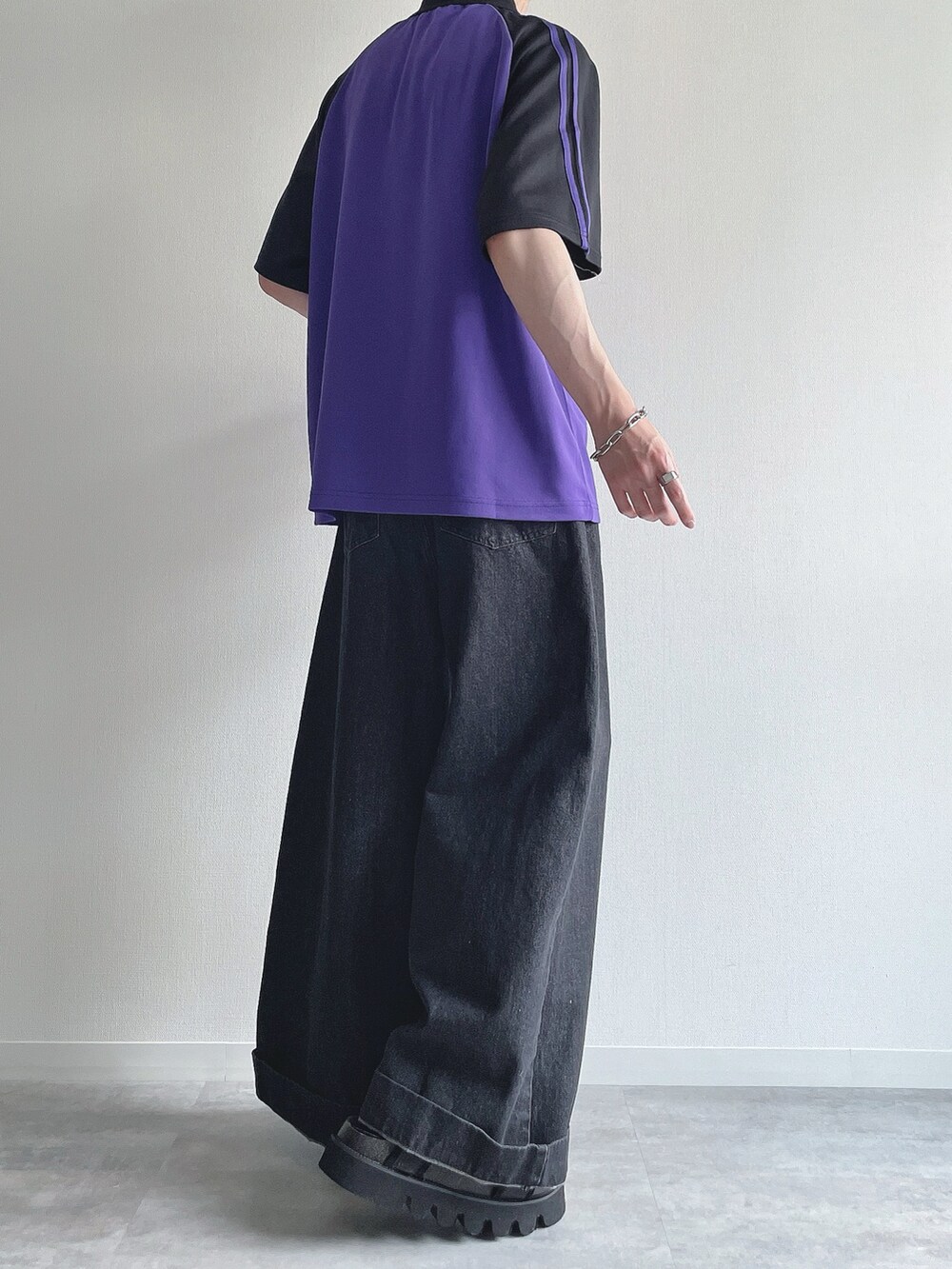 パープル系のTシャツ/カットソー、ブラック系のデニムパンツ、ブラック系のサンダルを着用したメンズの夏コーディネートの4枚目の写真