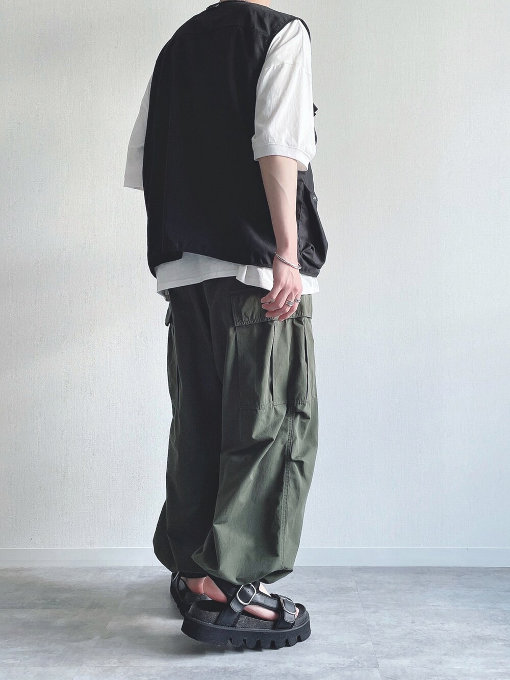 ブラック系のベスト、ホワイト系のTシャツ/カットソー、グリーン系のカーゴパンツを着用したメンズの夏コーディネートの3枚目の写真