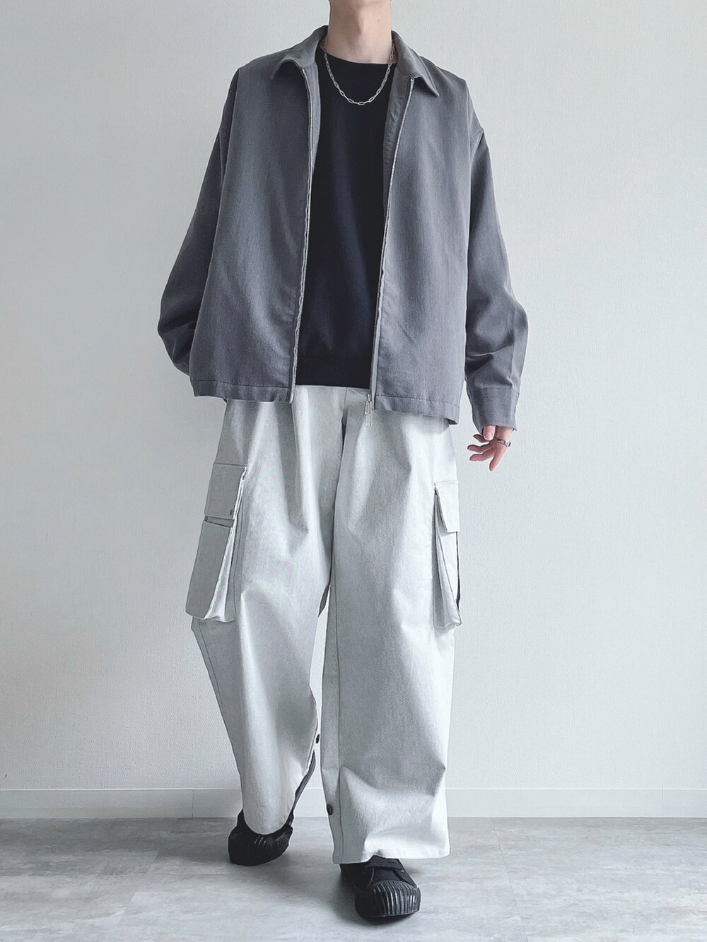 グレー系のブルゾン、ブラック系のトップス、ホワイト系のカーゴパンツを着用したメンズの春コーディネートの4枚目の写真