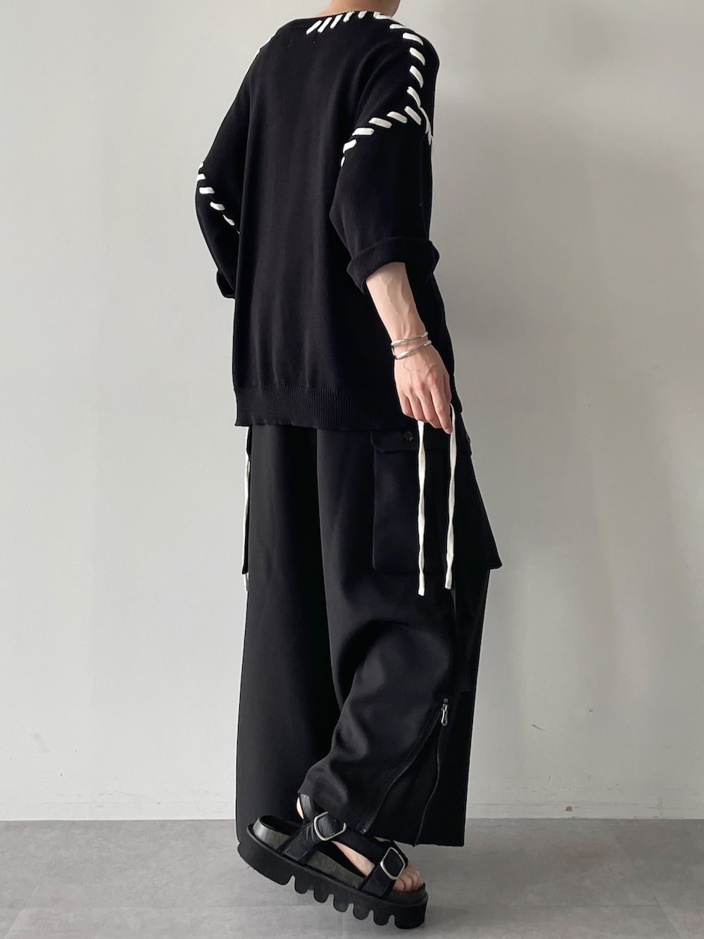 ブラック系のニット/セーター、ブラック系のその他パンツ、ブラック系のサンダルを着用したメンズの春コーディネートの4枚目の写真