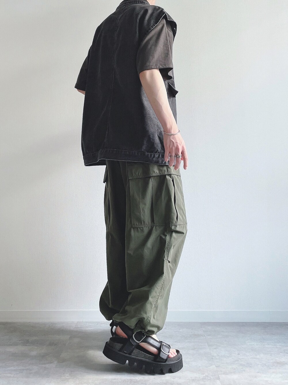 ブラック系のベスト、ブラック系のTシャツ/カットソー、グリーン系のカーゴパンツを着用したメンズの夏コーディネートの4枚目の写真