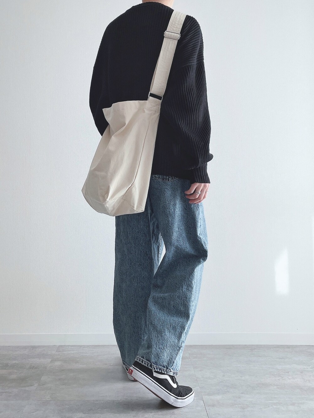 ブラック系のニット/セーター、ブルー系のパンツ、ブラック系のスニーカーを着用したメンズの冬コーディネートの3枚目の写真