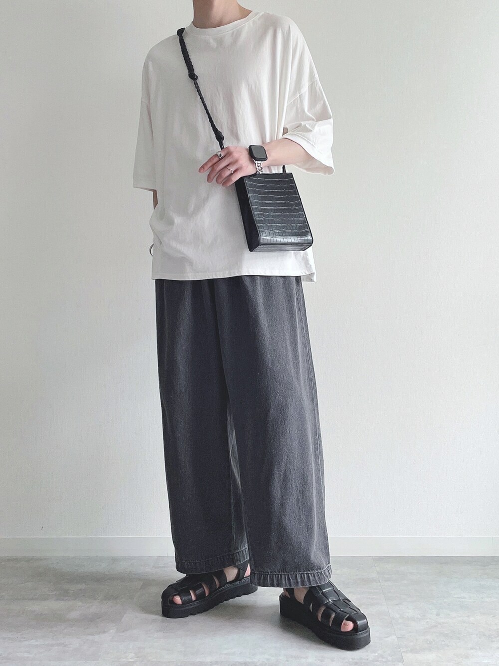 ホワイト系のTシャツ/カットソー、ブラック系のデニムパンツ、ブラック系のサンダルを着用したメンズの夏コーディネートの4枚目の写真