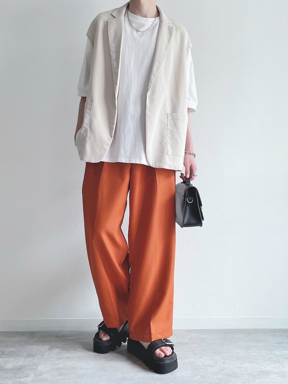 ホワイト系のベスト、ホワイト系のTシャツ/カットソー、オレンジ系のスラックスを着用したメンズの夏コーディネートの4枚目の写真