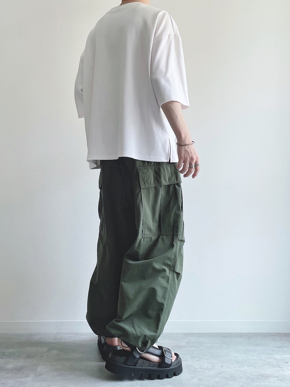 ホワイト系のTシャツ/カットソー、グリーン系のカーゴパンツ、ブラック系のサンダルを着用したメンズの夏コーディネートの3枚目の写真