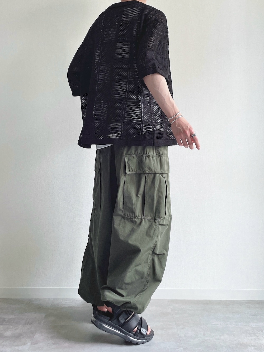 ブラック系のトップス、ホワイト系のタンクトップ、グリーン系のカーゴパンツを着用したメンズの春コーディネートの4枚目の写真