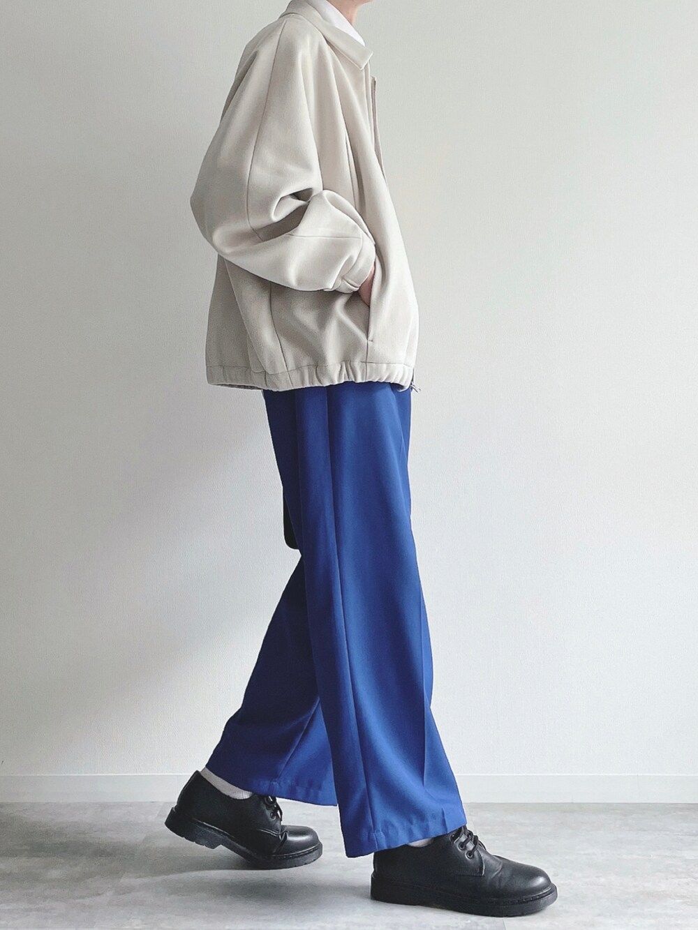 ホワイト系のブルゾン、ホワイト系のTシャツ/カットソー、ブルー系のスラックスを着用したメンズの冬コーディネートの2枚目の写真