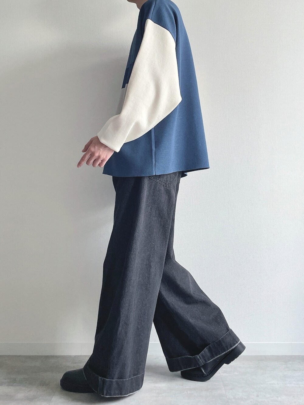 ブルー系のポロシャツ、ブラック系のデニムパンツ、ブラック系のシューズを着用したメンズの秋コーディネートの3枚目の写真